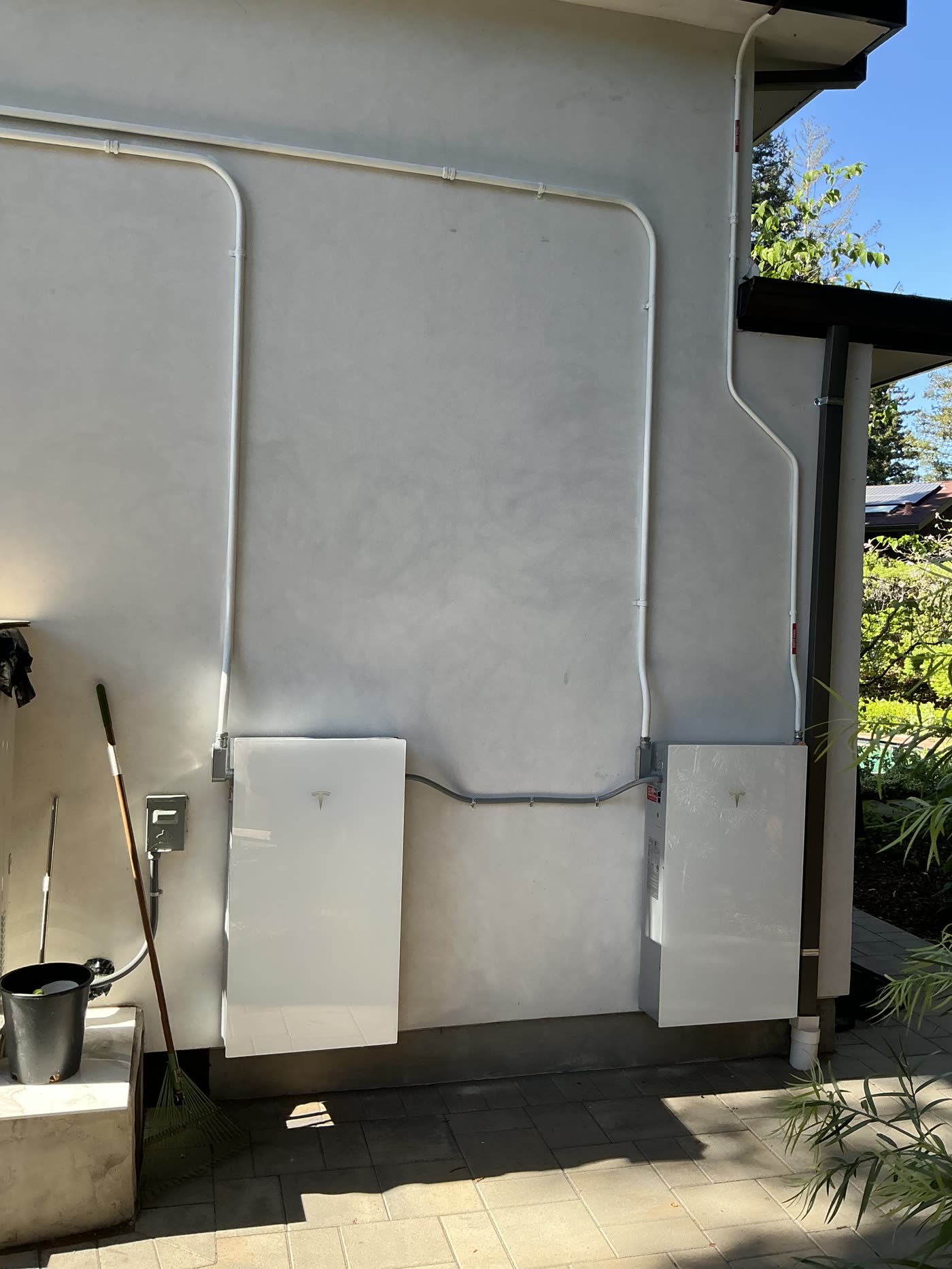 Two wall-mounted home batteries with conduit on an exterior wall